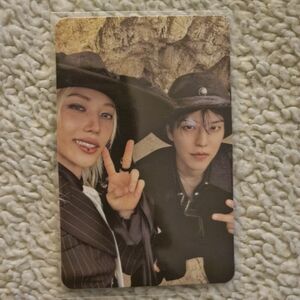 Photocard featuring two smiling people in black and brown outfits